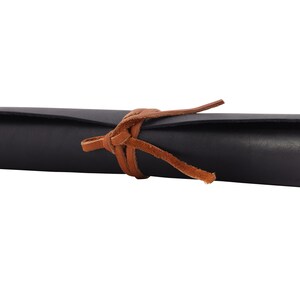 May include: A black leather roll with a brown leather strap tied around it.