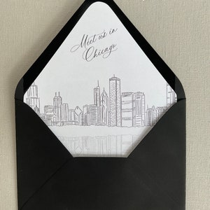 May include: A black envelope with a white insert featuring a line drawing of the Chicago skyline and the text "Meet us in Chicago".