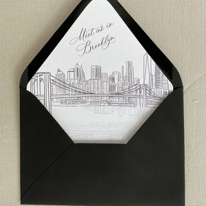 May include: A black envelope with a white insert. The insert features a line drawing of the New York City skyline with the Brooklyn Bridge and the text "Meet us in Brooklyn".