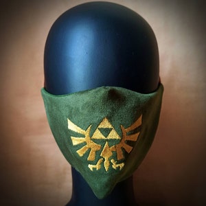 May include: Green fabric face mask with a gold embroidered Triforce symbol from the Legend of Zelda video game series.