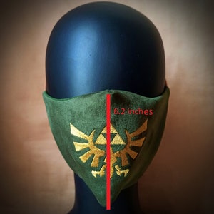 May include: Green fabric face mask with a gold embroidered Triforce symbol. The mask measures 6.2 inches wide.