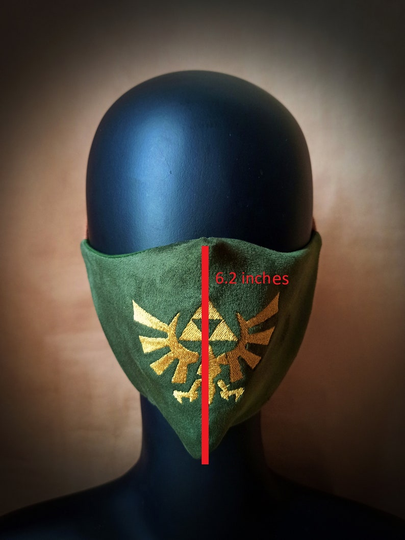 May include: Green fabric face mask with a gold embroidered Triforce symbol. The mask measures 6.2 inches wide.