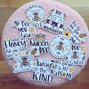May include: A collection of bee-themed stickers with various designs and phrases. The stickers feature illustrations of bees, sunflowers, and honeycomb patterns. Text includes "Always Bee Your Best," "Queen Bee," and "Bee Kind."