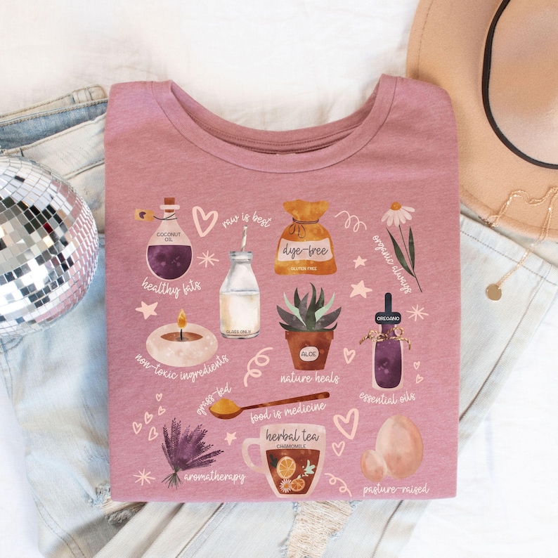 Holistic Wellness shirt that's a collage of all the basics of natural, holistic health. There's sweet watercolor graphics with cheeky text that look beautiful on the heather mauve tee. Comes in sizes S-4XL.