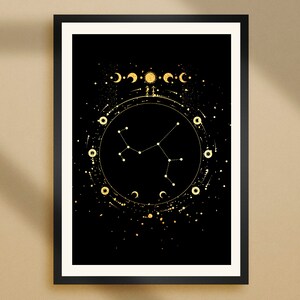 May include: A framed art print with a celestial theme. The artwork displays a black backdrop adorned with gold constellations, moons, and stars. The print is set within a black frame and a white border, offering a strong visual contrast.