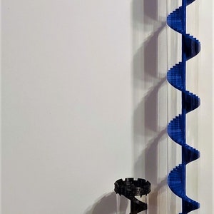 May include: Four different sized clear plastic containers with a spiral staircase inside. The containers are red, green, black, and blue.