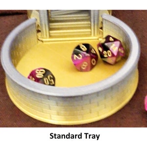May include: A gray and yellow plastic tray with a stone-like texture. The tray has three purple and gold dice inside.