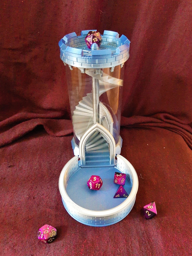 May include: A blue and silver 3D printed dice tower with a spiral staircase inside. The tower has a removable tray at the bottom to catch the dice. Four purple and gold dice are scattered around the tower.