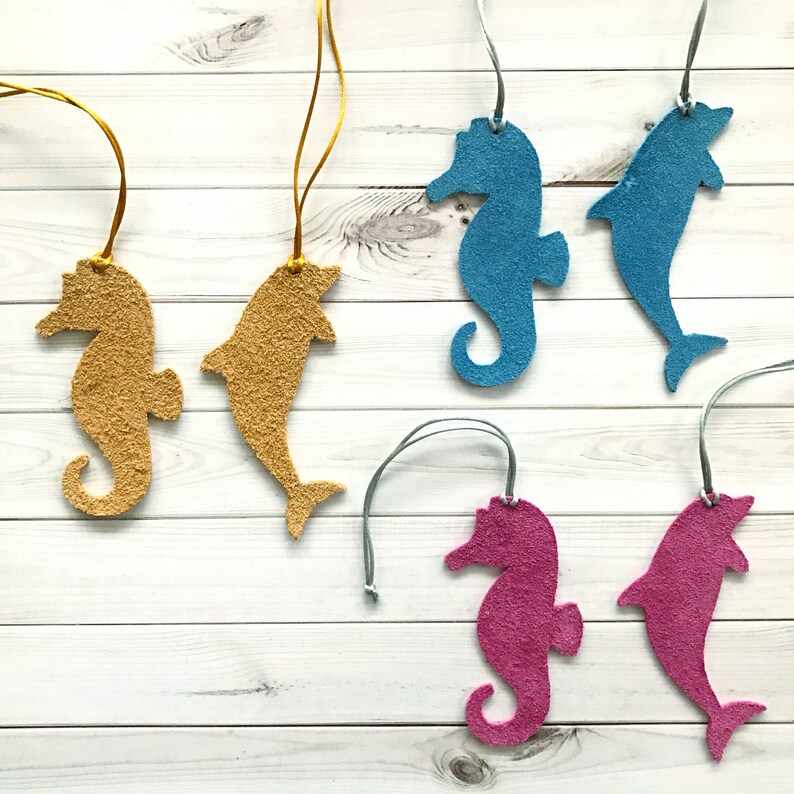 May include: Four felt seahorse and dolphin ornaments in blue, pink, and gold colors. Each ornament has a string attached for hanging.