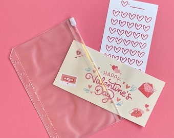 May include: A clear plastic zippered pouch with a gold zipper pull, containing a card with the text "Happy Valentine's Day" and a sheet of pink heart stickers.
