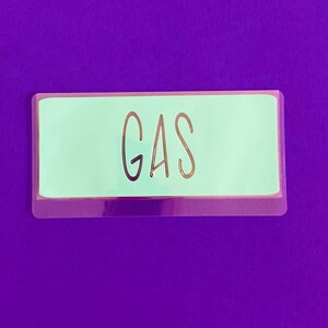 May include: A light green label with the word "GAS" printed in black on a purple background.