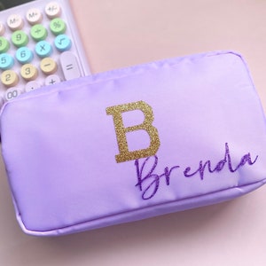 May include: A lavender zippered pouch with a gold glitter letter B and the name Brenda in gold glitter lettering.