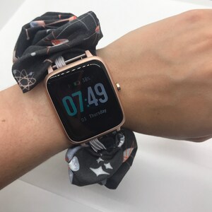 May include: A black and white patterned fabric wristband with a rose gold smartwatch displaying the time 07:49 and the date 03 Thursday. The battery is at 38%.