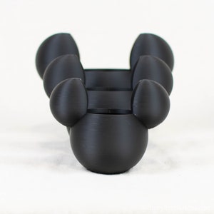 May include: Three black, 3D printed, Mickey Mouse-shaped candle holders. Each holder has a round base and two rounded ears.