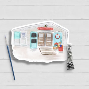 May include: A watercolor illustration of a beach market with a red sign that says "Beach Market". The market has a blue door and two windows. There are beach toys and a red bucket in front of the market.