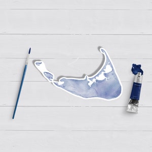 May include: A blue watercolor painting of an island shape on a white wooden background. A blue paint tube and a paintbrush are also on the surface.