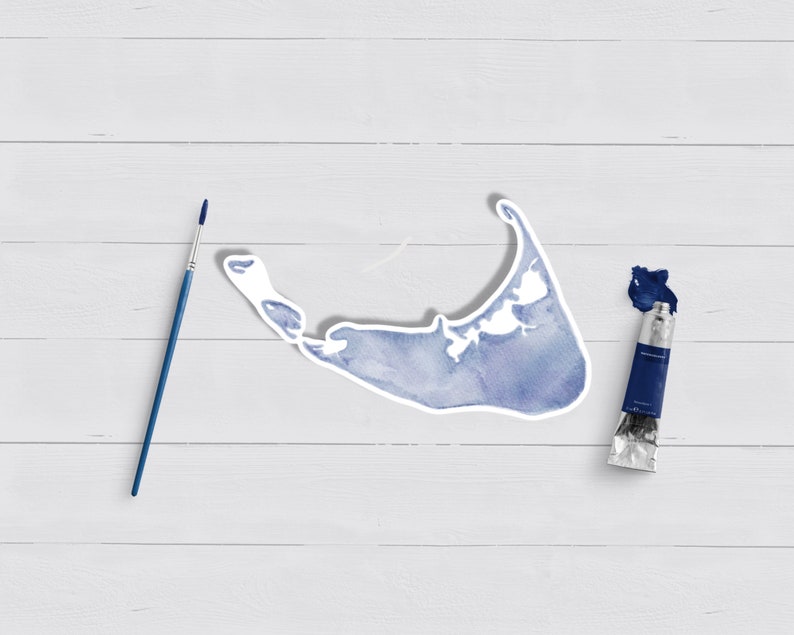 May include: A blue watercolor painting of an island shape on a white wooden background. A blue paint tube and a paintbrush are also on the surface.