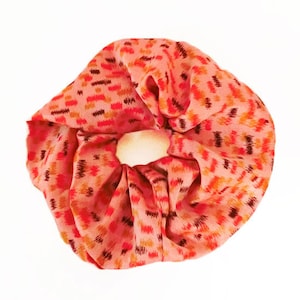 May include: A pink and orange patterned scrunchie with a woven design.