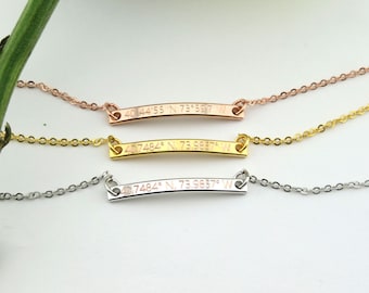 Puede incluir: Tres delicados collares con un colgante de barra con coordenadas grabadas. Los collares son de plata, oro y oro rosa.