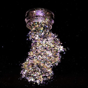 May include: A clear jar with a lid is spilling iridescent glitter onto a black background. The glitter is a mix of gold, silver, and purple.