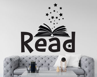 Puede incluir: Pegatina de pared en blanco y negro con la palabra "Read" y un libro abierto con estrellas saliendo de él. La pegatina está en una pared blanca sobre un sofá gris.