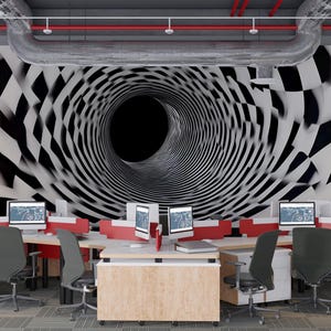 May include: An office space featuring multiple workstations with computers. The focal point is a black and white geometric mural creating a tunnel effect. Desks are light wood with red accents, and gray chairs are positioned throughout the room.