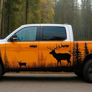 Puede incluir: Una camioneta blanca y naranja con un diseño de escena forestal. El diseño presenta siluetas de ciervos, árboles y una puesta de sol. La camioneta tiene ruedas negras y está estacionada en una carretera pavimentada.