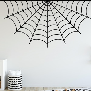 Peut inclure: Un autocollant mural en forme de toile d'araignée noire. La toile est en forme de demi-cercle, avec des lignes courbes rayonnant d'un point central. L'autocollant est appliqué sur un mur blanc dans une pièce au décor minimaliste.