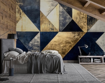 May include: A modern bedroom with a geometric accent wall featuring triangles in navy blue, gold, and white. The room includes a gray bed with a matching comforter, a side table, and a floor lamp. A gray rug covers the floor.
