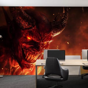 May include: A large wall mural featuring a fiery demon with glowing red eyes and horns dominates an office space. The office has a desk with two computer monitors, black chairs, and windows with blinds.