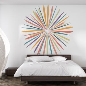 May include: A modern bedroom with a dark wood bed frame and white bedding. A large, colorful burst of painted lines in shades of orange, yellow, teal, and purple adorns the white wall above the bed. A sheer white curtain is blowing in the wind.