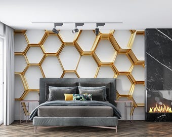 May include: A modern bedroom featuring a gray bed with pillows and a patterned throw. The headboard is set against a wall with a gold honeycomb design. A fireplace with a marble surround and a decorative side table complete the room.