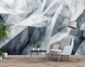 Puede incluir: Un salón moderno con un mural de pared de mármol geométrico en tonos grises y blancos. Un sillón gris, una pequeña mesa auxiliar y una lámpara de pie con pantalla blanca están en la habitación. Las plantas en macetas añaden un toque de vegetación.
