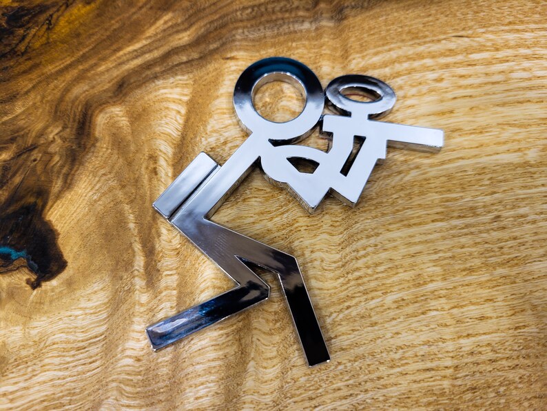 May include: A silver metal sculpture of a person holding a smaller person. The sculpture is on a wooden surface.