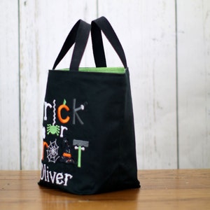 May include: Black trick or treat bag with green lining and embroidered text "Trick or Treat Oliver" with Halloween themed graphics.