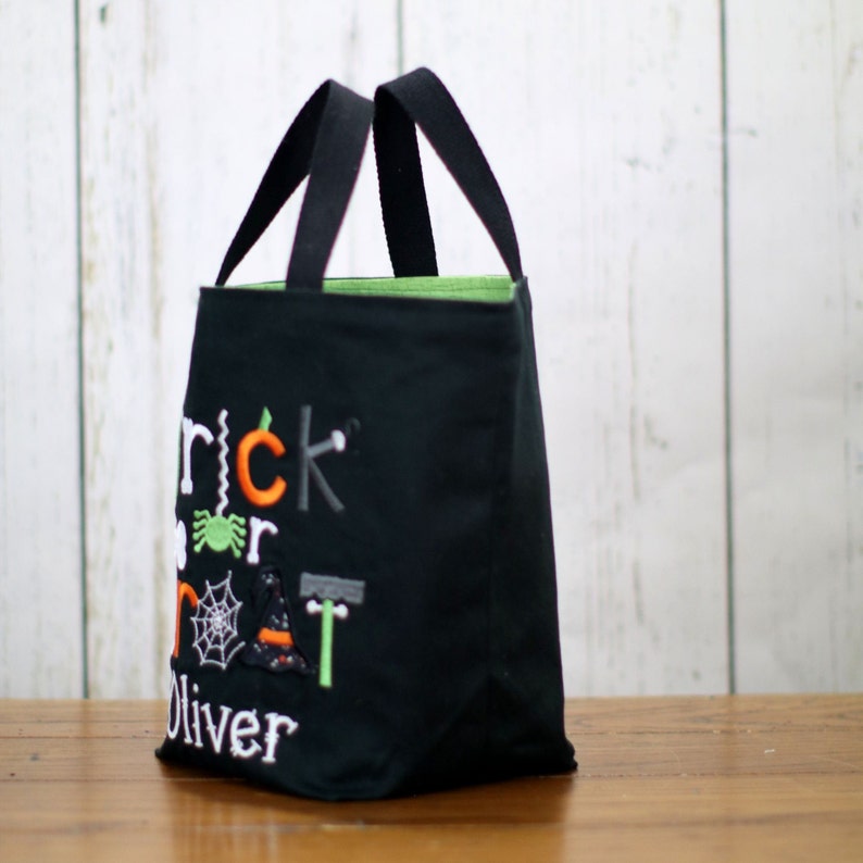 May include: Black trick or treat bag with green lining and embroidered text "Trick or Treat Oliver" with Halloween themed graphics.
