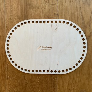Könnte beinhalten: Ein ovaler Sockel aus hellem Holz mit Löchern am Rand zum Häkeln. Der Sockel trägt den Text "Le Loup Creations" und "Tote Bag Handwerk Ein Unikat" eingraviert.