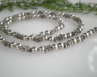 May include: A silver necklace with alternating round and textured beads.