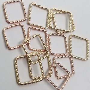 May include: A group of 12 gold and rose gold twisted square hoops. The hoops are all the same size and are arranged in a random pattern.