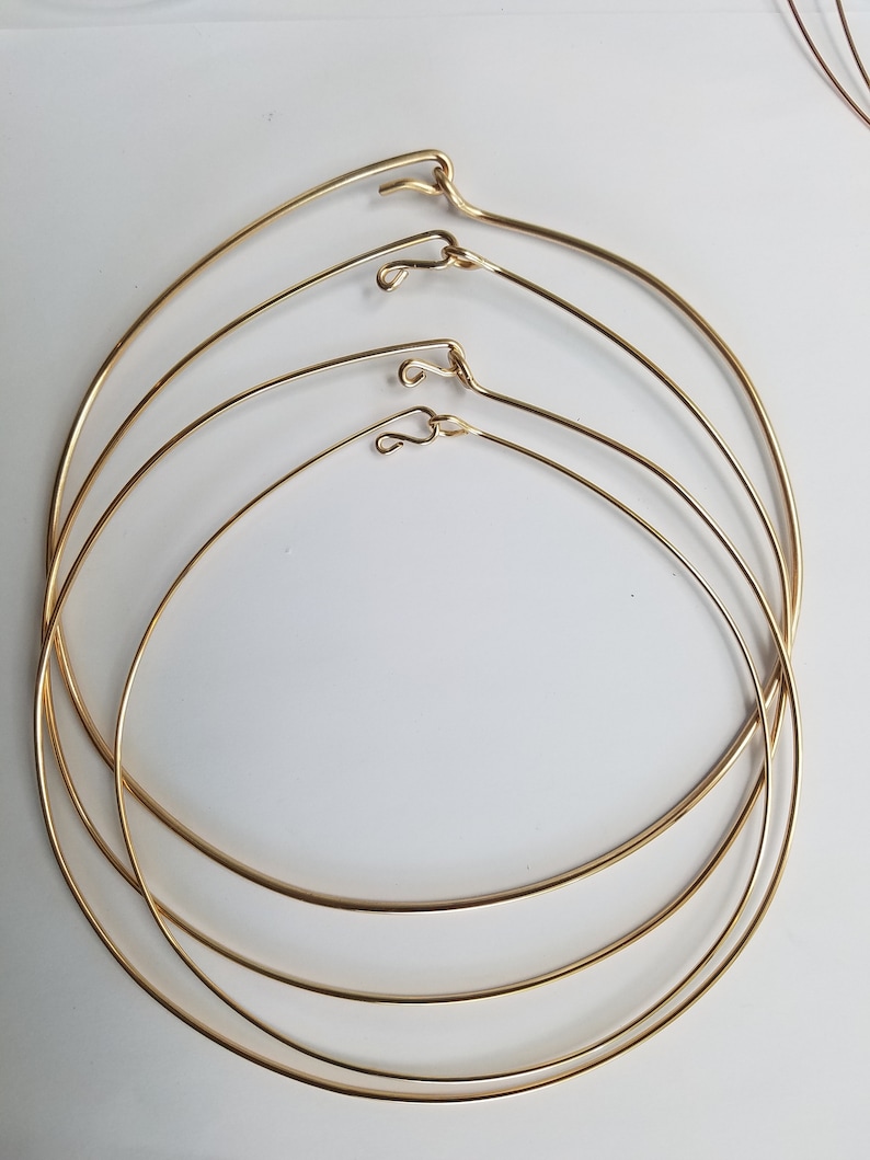 K&ouml;nnte beinhalten: Vier goldfarbene Metallreifen in verschiedenen Gr&ouml;&szlig;en, jeder mit einem kleinen Haken oben.
