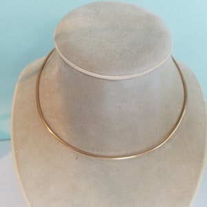 K&ouml;nnte beinhalten: Eine goldfarbene Choker-Kette auf einer Schaufensterpuppe.