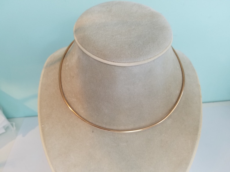 K&ouml;nnte beinhalten: Eine goldfarbene Choker-Kette auf einer Schaufensterpuppe.