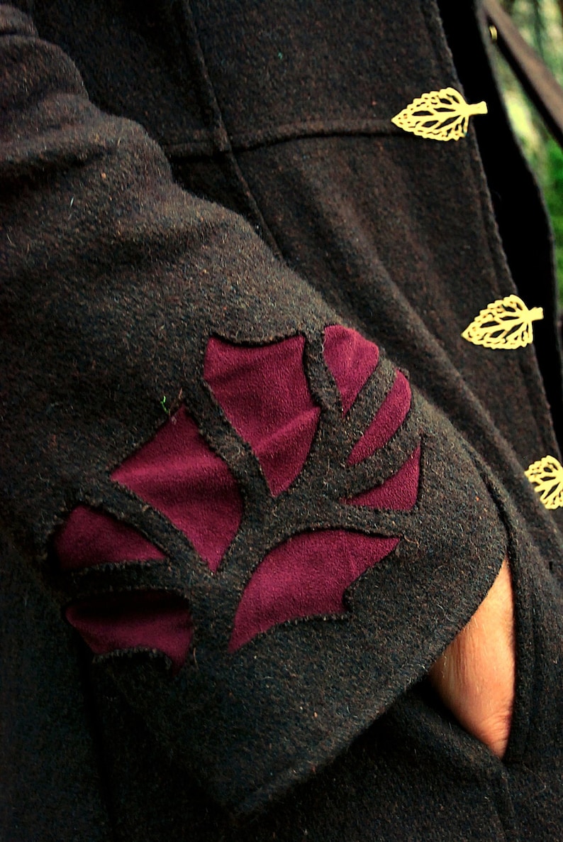 May include: A dark brown jacket with a burgundy leaf design on the sleeve. The jacket has gold leaf-shaped buttons.