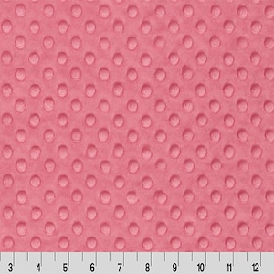 May include: Pink minky fabric with a raised dot pattern. The fabric is shown with a ruler along the bottom, with markings in inches. The fabric is a solid color and has a soft, plush texture.