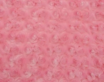 May include: Close-up of a pink fabric with a rose pattern. The fabric has a soft, textured appearance, with the rose shapes creating a three-dimensional effect. The color is a vibrant, light pink.
