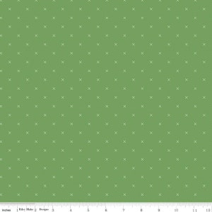 May include: Green fabric with a repeating pattern of small white crosses. The fabric has a smooth texture and is measured in inches along the bottom edge. The pattern is evenly spaced across the fabric.