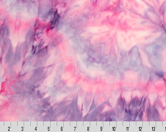 May include: A close-up of a fabric with a tie-dye pattern in shades of pink, purple, and white. The fabric has a soft, textured appearance. A ruler is at the bottom of the image, with markings from 1 to 15 inches.