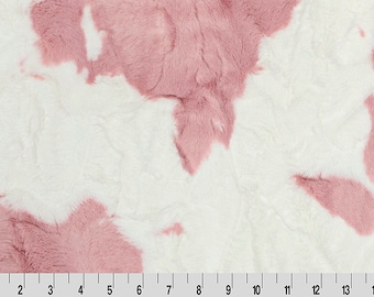 May include: A plush fabric with a white base and irregular patches of dusty rose. The material has a soft, textured appearance, with a ruler along the bottom edge showing measurements in inches. This textile is suitable for various craft projects.