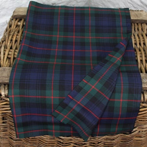 May include: A folded piece of green, blue and red tartan fabric. The fabric is folded in half and the edges are visible.