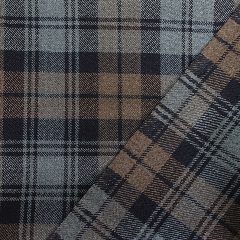 May include: Close-up of a fabric with a plaid pattern in shades of brown, black, and grey.